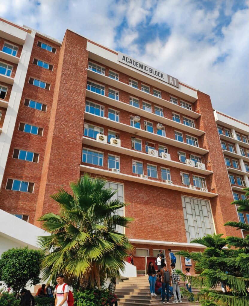 View of an academic building with palm trees and people in a sunny urban setting.