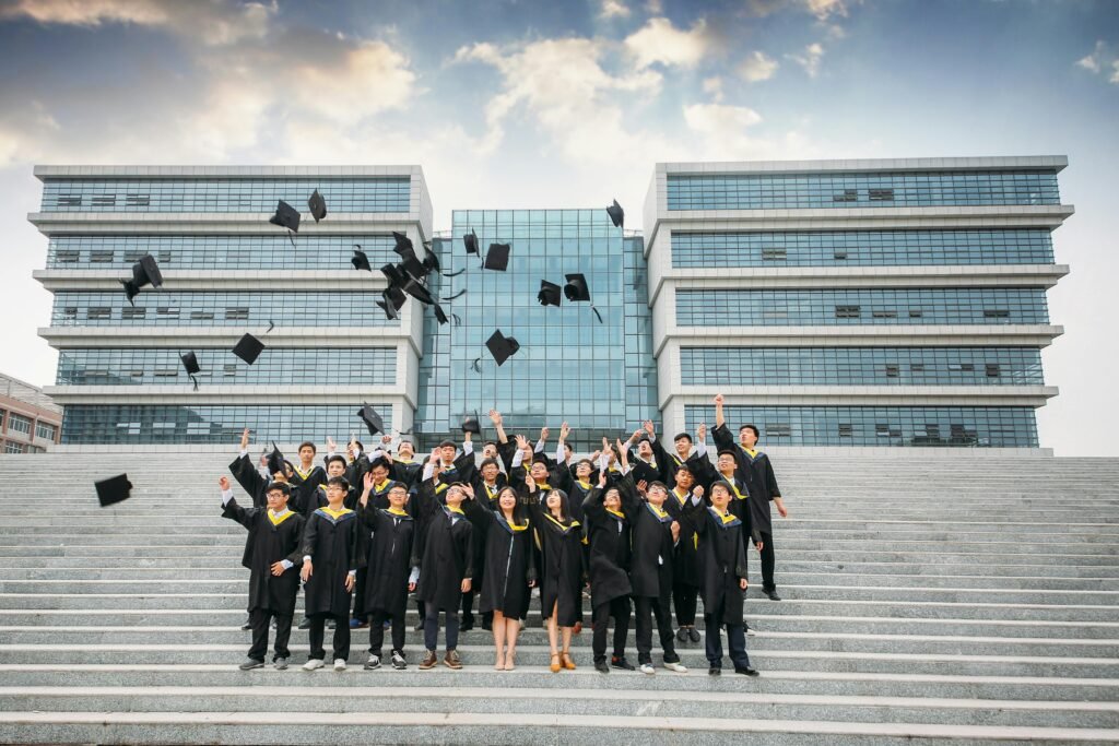 Group of graduates celebrating and tossing caps outside modern building.
