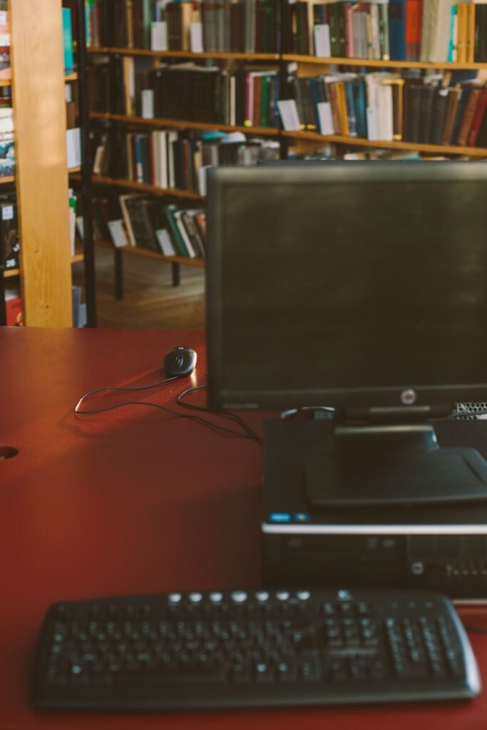 A computer setup on a desk in a library, ideal for research and study.