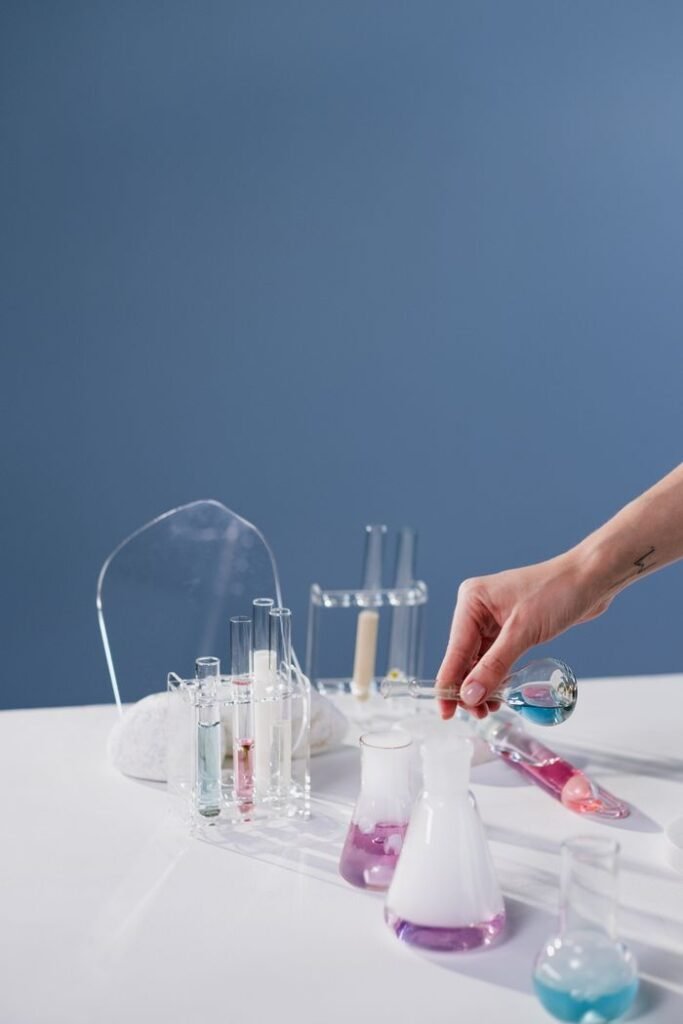 A hand pours blue liquid into a flask in a modern laboratory setting.